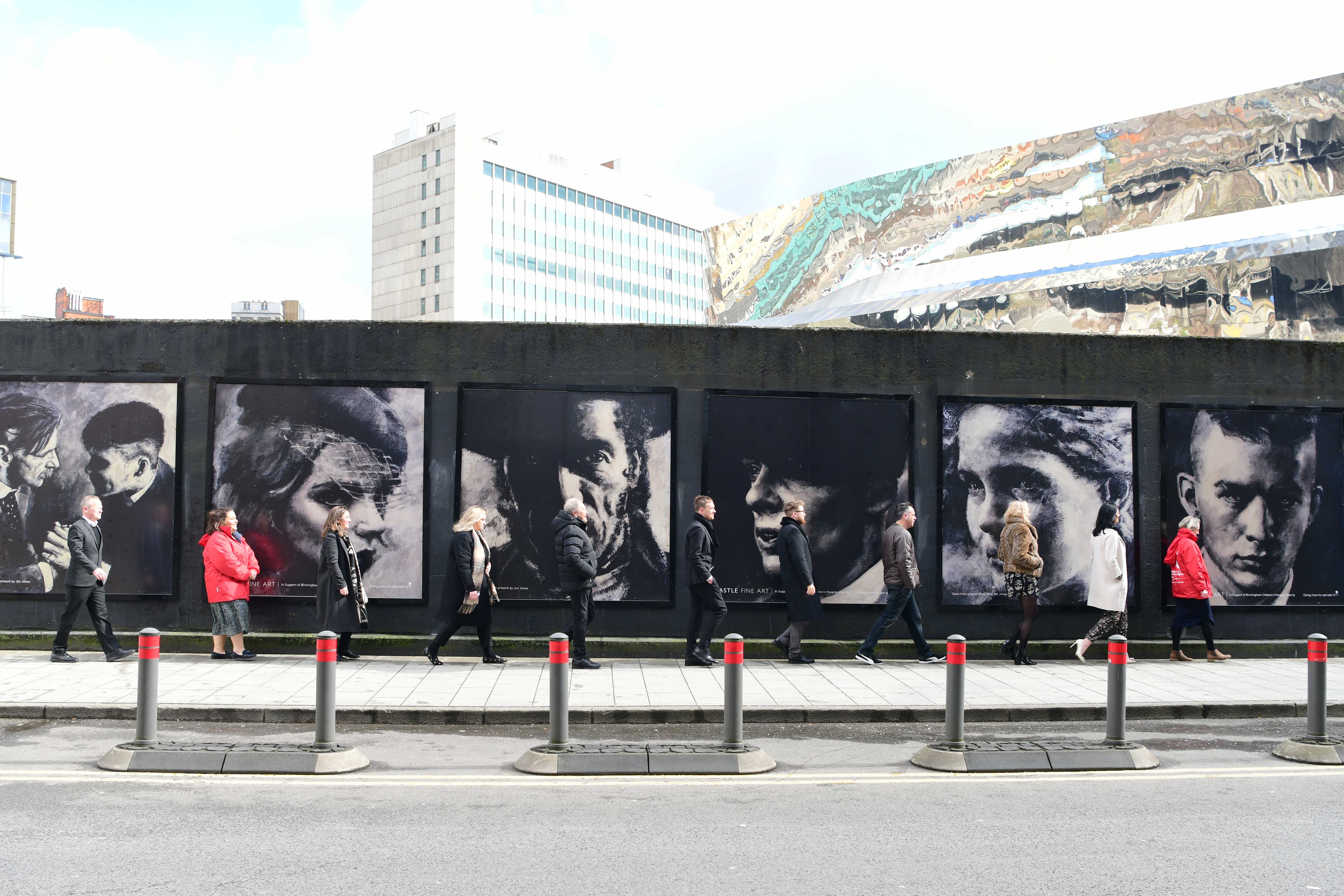 People walk by Jon Jones Peaky Blinders mural in Birmingham